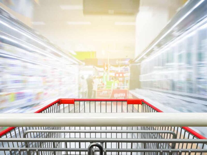 Supermarket aisle with empty red shopping cart