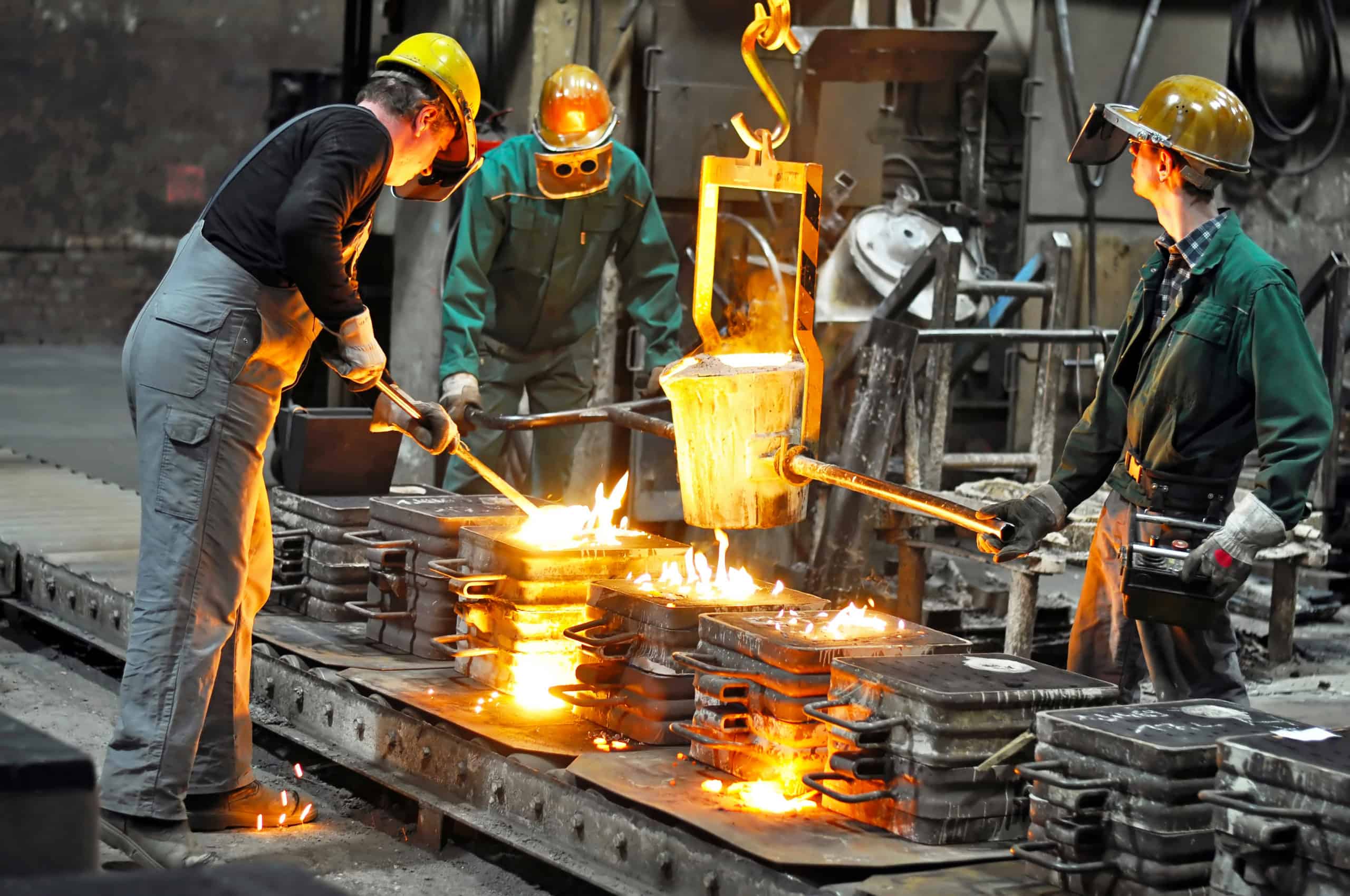 Group of workers in a foundry at the melting furnace - production of steel castings in an industrial company